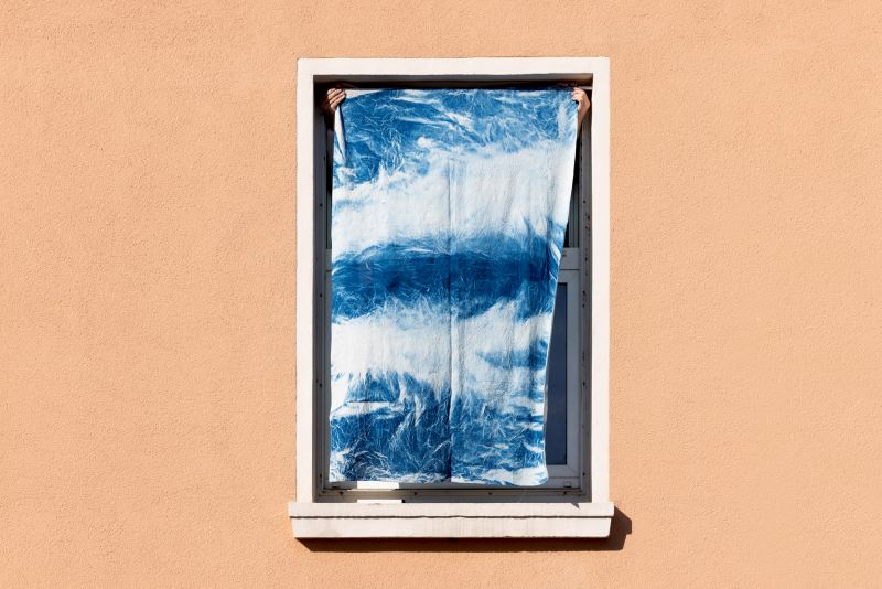 Detail of a window. Blue cyanotype is mounted on a rod and fitted into the window frame.